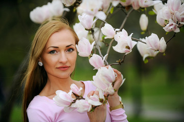 Fototapeta premium Beautiful, lovely and young woman at the flowers of tree branches in spring.