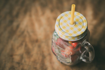 cherries in a glass cup with a straw on a dark wooden background, summer concepts with strawberries