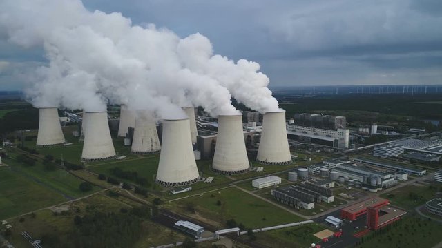 Panoramic drone flight over massive coal fired power plant (and some wind turbines in the background), in Janschwalde, Eastern Germany