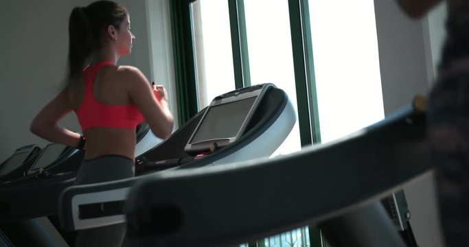Young woman running on treadmill during gym workout