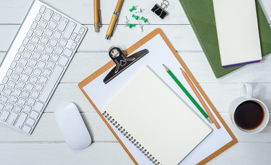 Wooden White office desk table with cup of coffee, Notebook, Pen on it.