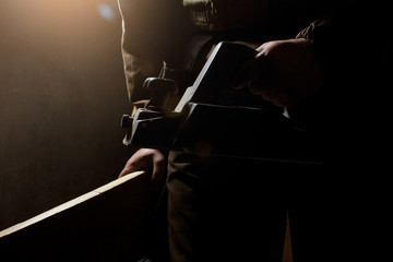 Photo of a worker in outfit with blue gloves standing with electrical plane on black background with upper light and side view.