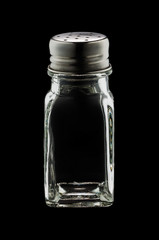 An empty glass shaker of salt isolated on black background