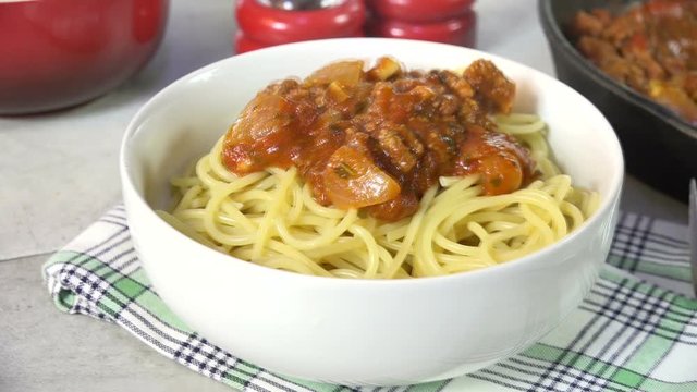 Spooning spaghetti sauce onto pasta, slow motion