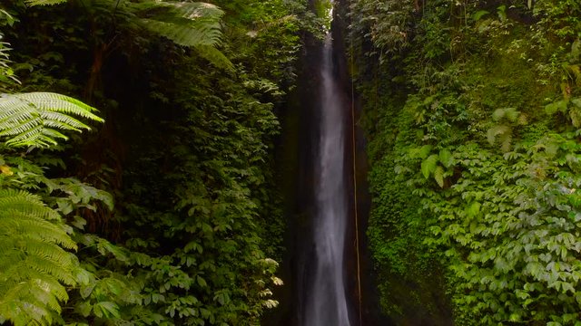 Aerial View of the Leke Leke waterfall in jungles of Bali, Indonesia. Drone moves backwards and camera tilts down