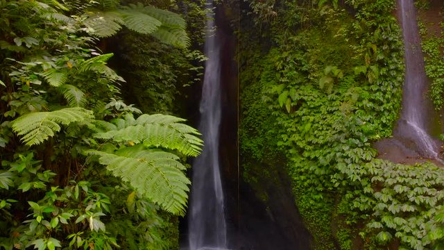 Aerial View of the Leke Leke waterfall in jungles of Bali, Indonesia. Drone moves to the left