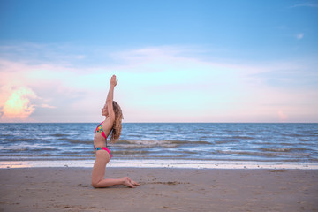 Young healthy woman with blonde curly hair doing yoga on the beach, heathy and relaxing concept.