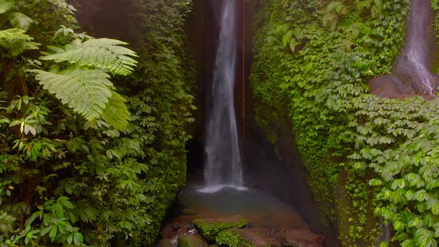 Aerial View of the Leke Leke waterfall in jungles of Bali, Indonesia. Drone slowly moves to the left