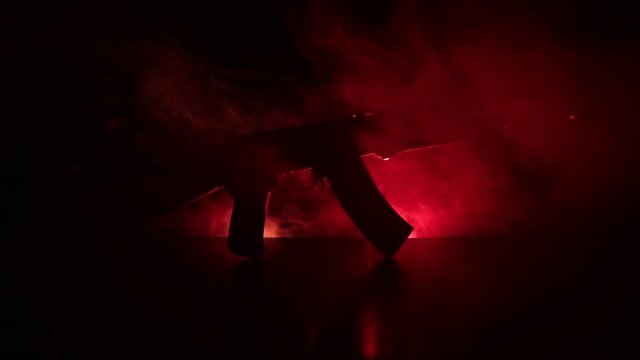 Silhouette of assault rifle on toned foggy background. War or antiterrorism concept. Russian military weapon on table. Slider shot