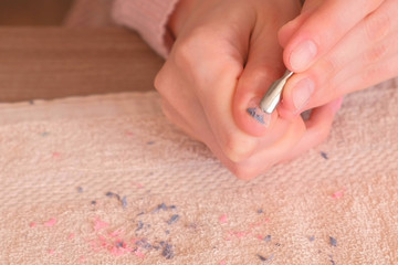 Woman removes shellac from nail with pusher. Close-up hand.