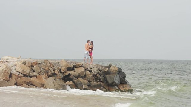 young couple standing on stones against the sea