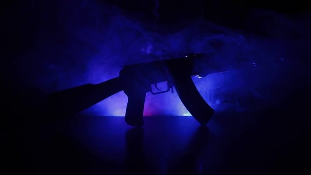 Silhouette of assault rifle on toned foggy background. War or antiterrorism concept. Russian military weapon on table. Slider shot