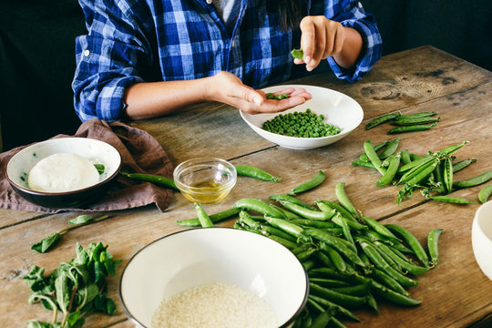 Healthy food concept Woman cooking vegetarian risotto green peas mint goat cheese Rustic style Raw ingredients cooking risotto wooden table