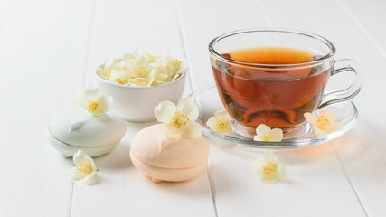 Marshmallow macaroons with tea and Jasmine flowers on a white wooden table.