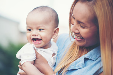 Mother throws baby up, laughing and playing in the park