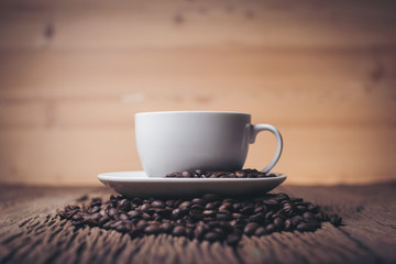 Coffee cup with coffee beans on wood table.