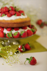 Homemade strawberry cake with cream on a glass stand.