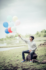 Young man hand holding colorful balloons