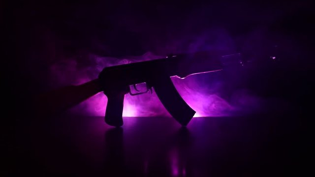 Silhouette of assault rifle on toned foggy background. War or antiterrorism concept. Russian military weapon on table. Slider shot