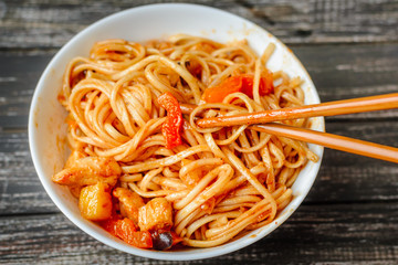 Chinese noodle in sour-sweet sauce and chopsticks on table