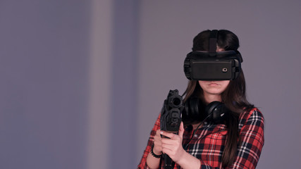 Girl wearing virtual reality glasses and holding a vr gun