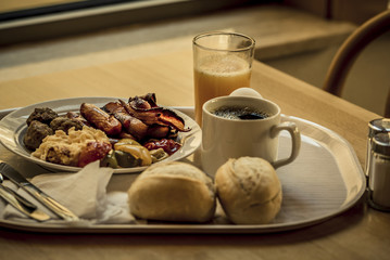 Boiled eggs ,sausages, meat ball, Bread and bacon, Orange juice, Cup of black coffee, Sliced Sweet Pepper and ham on plate, healthy breakfast.