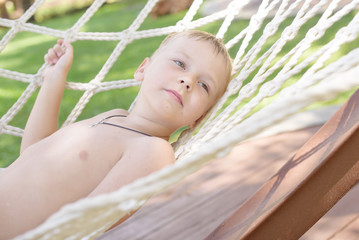 cute little boy is resting in a hammock