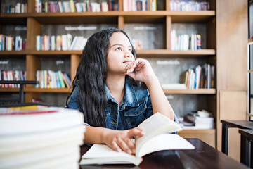 Young woman reading book sitting indoor in urban cafe.