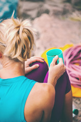 The climber is drinking from a mug.