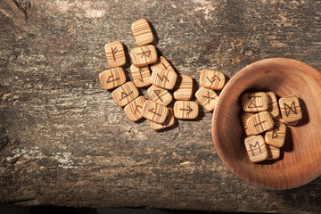Runes in a wooden plate on a textured old textured wooden surface