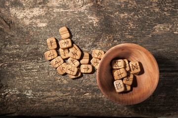Runes in a wooden plate on a textured old textured wooden surface
