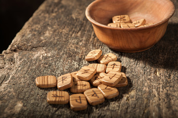 Runes in a wooden plate on a textured old textured wooden surface