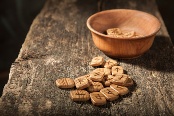 Runes in a wooden plate on a textured old textured wooden surface