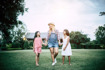 Obraz premium Mother and two daughter walk and playing in the house garden