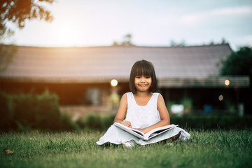 Little girl reading a book in the house garden