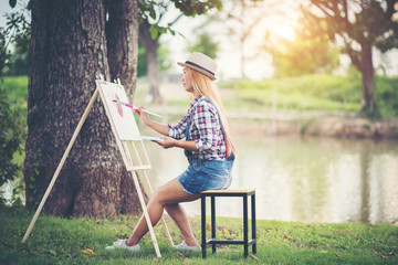 Beautiful girl draws a picture in the park