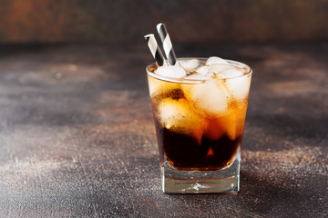 Cold Cola in glass with ice cubes on dark old concrete background.