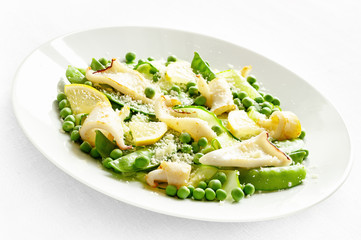 fried calamari salad with pea, pea pods,lemon, cucumber decorated with grated cheese and dressed with oil and vinegar