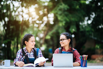 Fototapeta premium Two students studying together online with a laptop in the park