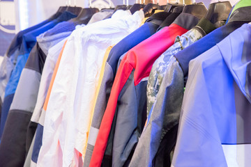 The upper work clothes of strong fabric of different colors with pockets hang on the hangers as a sample