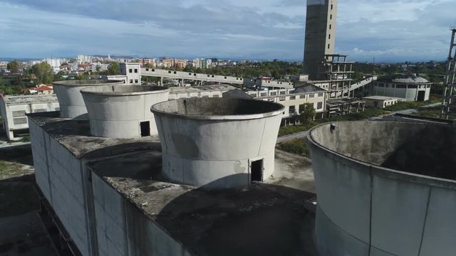 Aerial view of neglected cooling towers of large power plant, nitrogen production facility, and various other factories in Fier, central Albania 