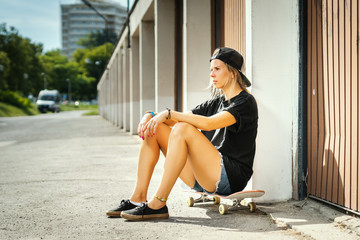 Fototapeta na wymiar girl is sitting on a skateboard and is resting on a summer day