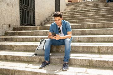 happy young student male texting on his smart phone in modern city