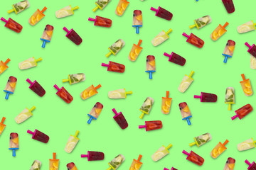 Pattern of fruit popsicles on a green background. Strawberry, Lemon, Lemon with mint, Orange, Cherry, Multifruit. Flat lay, top view