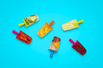 Homemade healthy fruit popsicle on a blue background. Strawberry, Lemon, Lemon with mint, Orange, Cherry, Multifruit. Flat lay, top view