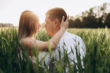 The lovely couple in love embracing and sitting on the grass