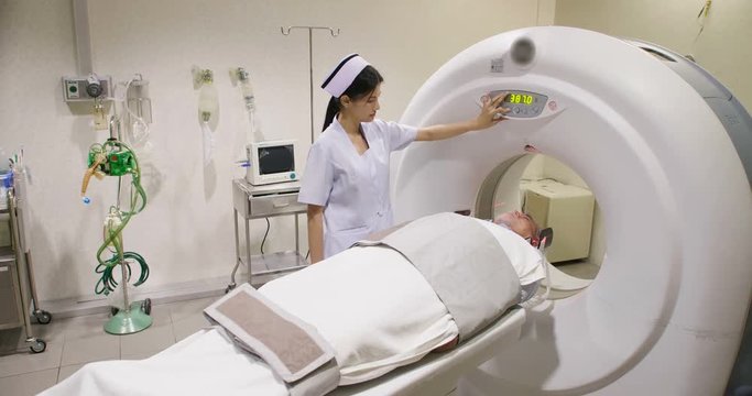 Middle aged man lying on the CT scanner during machine imaging his body, lights up infrared rays and male patient passes through the circle.