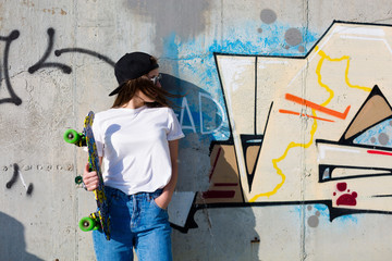 Obraz na płótnie Canvas Woman with a skateboard standing near the wall
