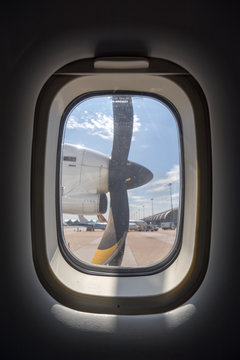 Propeller and engine of vintage airplane, seen through an airplane window from the passenger seat.