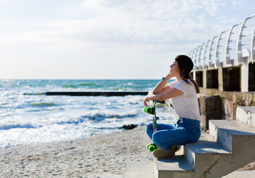 Woman with a skateboard on a beach - Powered by Adobe